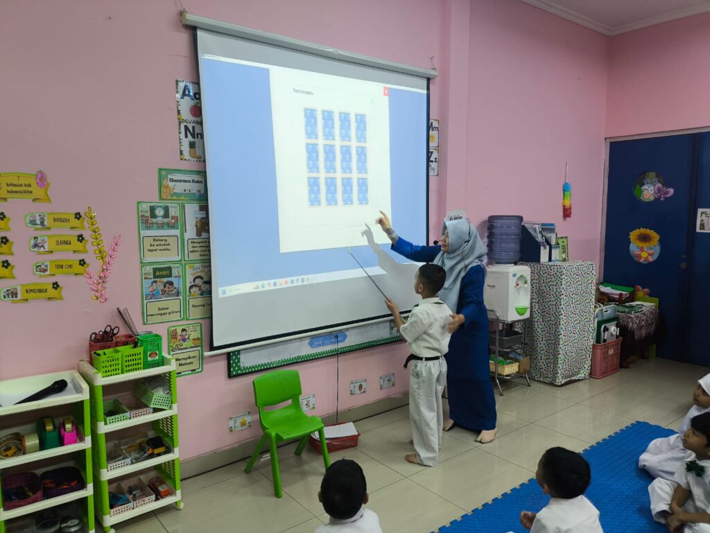 Guru TK Islam Al Azhar 17 Bintaro mengajak murid mengikuti pembelajaran interaktif dengan media proyektor